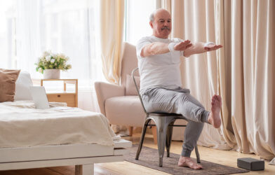 Older man doing chair yoga with online class