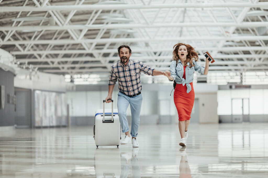 Couple running with luggage to airport gate
