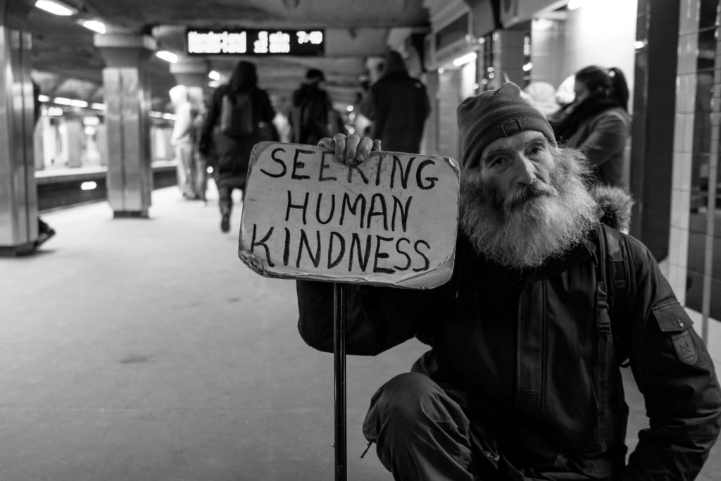 Homeless man holding sign asking for kindness