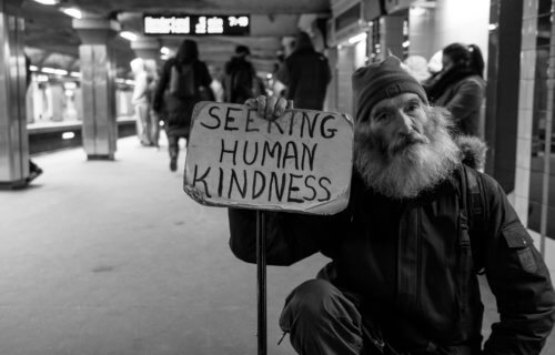 Homeless man holding sign asking for kindness