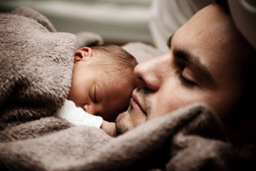 Father sleeping with his newborn baby
