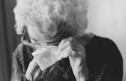 Elderly woman wiping a tear from her eyes